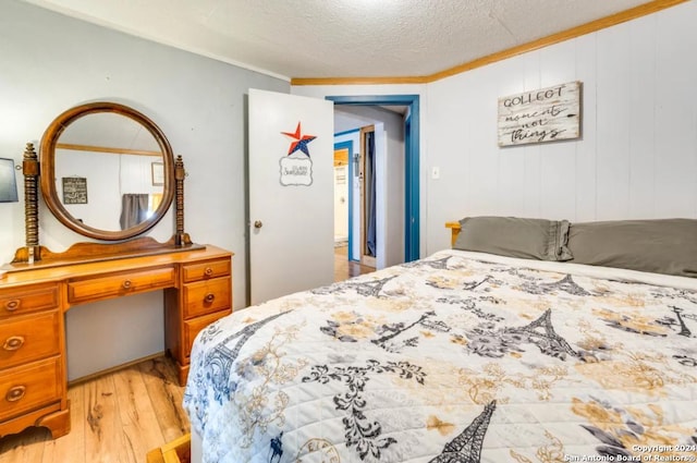 bedroom featuring light wood-style flooring, ornamental molding, and a textured ceiling