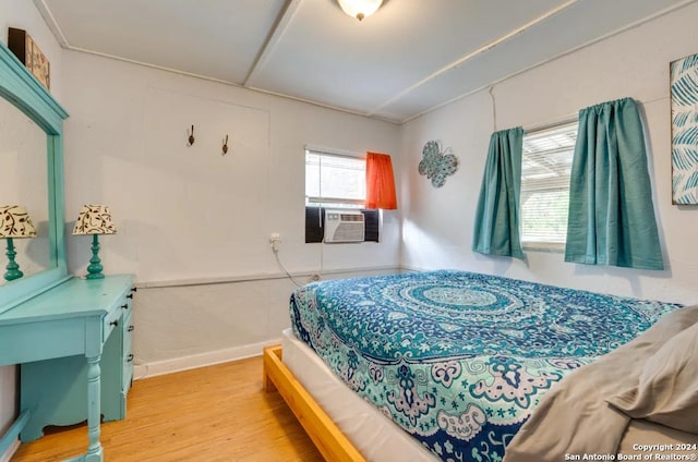 bedroom with cooling unit and light wood finished floors