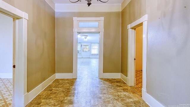 hall with ornamental molding and a notable chandelier