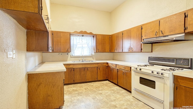 kitchen with sink, light tile patterned flooring, white gas range, and a high ceiling