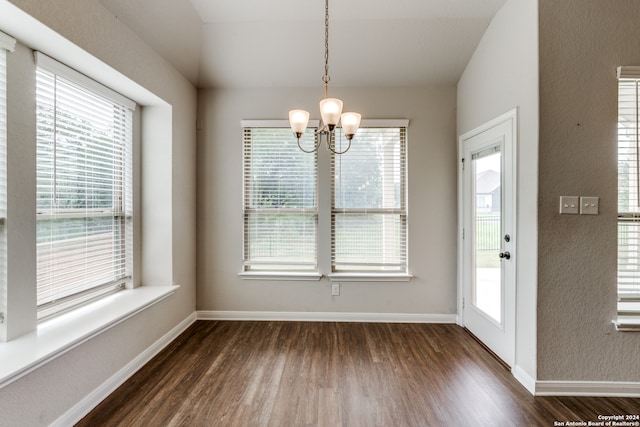 unfurnished dining area featuring a notable chandelier and dark hardwood / wood-style flooring