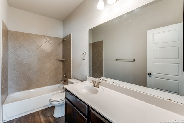 full bathroom with vanity, toilet, tiled shower / bath, and hardwood / wood-style floors