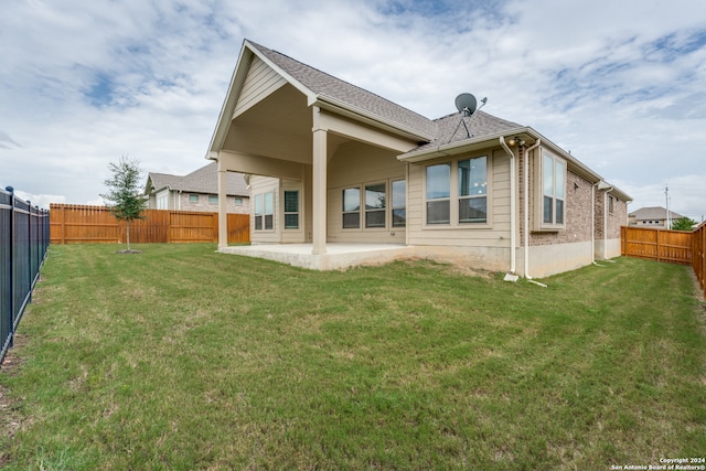 back of house with a patio and a lawn