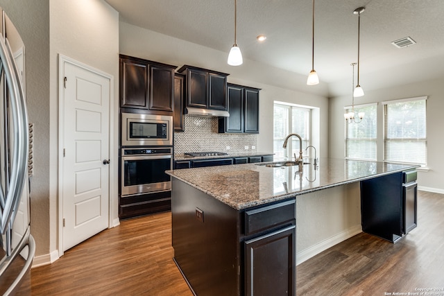 kitchen featuring backsplash, dark hardwood / wood-style flooring, an island with sink, appliances with stainless steel finishes, and sink