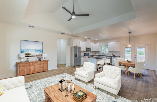 living room featuring ceiling fan, high vaulted ceiling, and light wood-type flooring