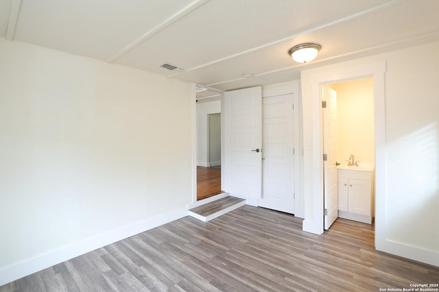 unfurnished bedroom with connected bathroom, sink, and light wood-type flooring