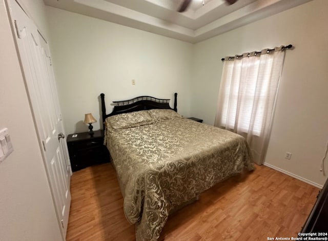 bedroom featuring hardwood / wood-style flooring, a tray ceiling, and ceiling fan