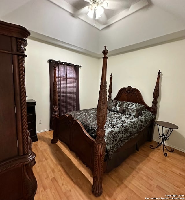 bedroom featuring light hardwood / wood-style floors, a tray ceiling, and ceiling fan