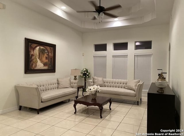 tiled living room featuring ceiling fan and a raised ceiling