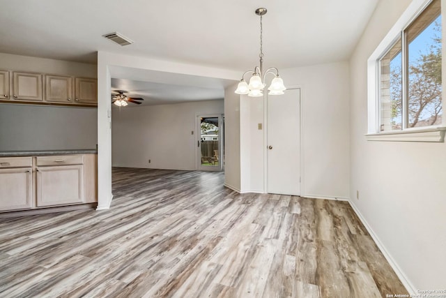 unfurnished dining area with ceiling fan with notable chandelier and light hardwood / wood-style flooring