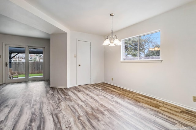 unfurnished dining area with a chandelier and light hardwood / wood-style flooring