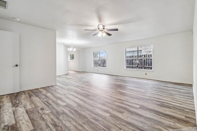 unfurnished room with ceiling fan with notable chandelier and light hardwood / wood-style floors