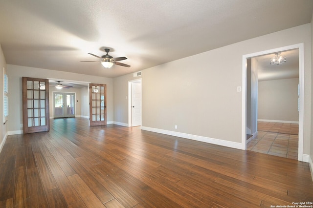 unfurnished room featuring dark hardwood / wood-style floors, ceiling fan with notable chandelier, french doors, and a textured ceiling