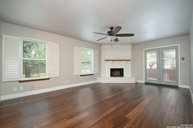 unfurnished living room featuring french doors, a fireplace, a healthy amount of sunlight, and dark hardwood / wood-style floors