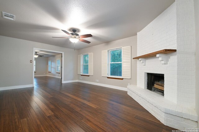 unfurnished living room featuring ceiling fan, dark wood-type flooring, a textured ceiling, and a fireplace