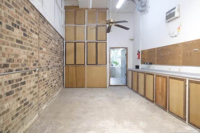 interior space with ceiling fan, brick wall, and a wall mounted AC