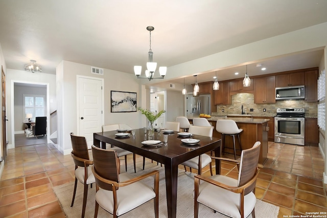 dining area featuring tile patterned flooring, sink, and a chandelier