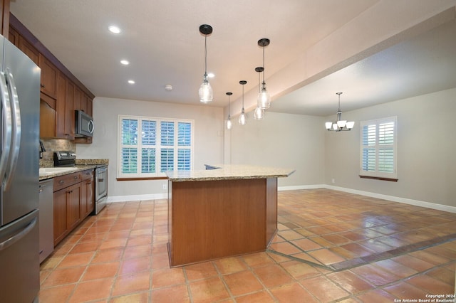 kitchen with appliances with stainless steel finishes, an inviting chandelier, tasteful backsplash, light stone counters, and decorative light fixtures