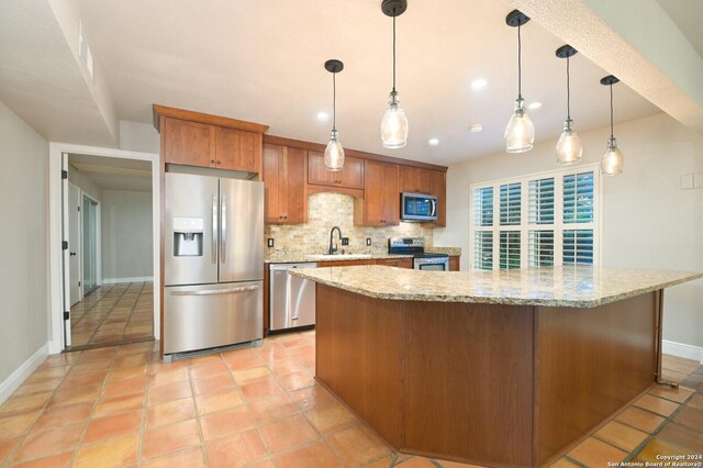 kitchen with appliances with stainless steel finishes, tasteful backsplash, sink, hanging light fixtures, and light stone countertops