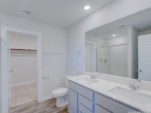 bathroom featuring wood-type flooring, an enclosed shower, vanity, and toilet