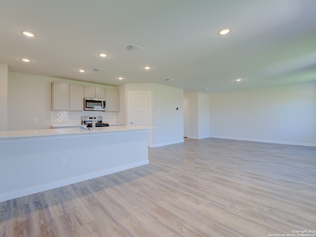 kitchen featuring decorative backsplash, light hardwood / wood-style floors, white cabinets, and appliances with stainless steel finishes