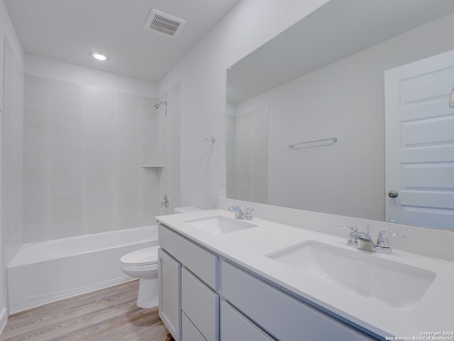 full bathroom featuring wood-type flooring, toilet, tiled shower / bath, and vanity