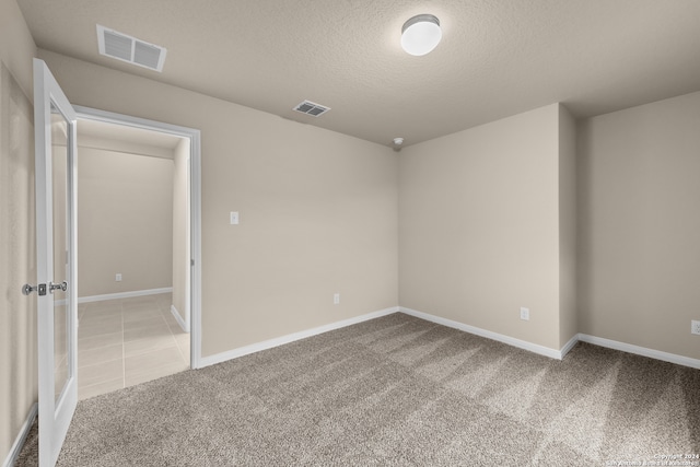 carpeted empty room featuring a textured ceiling