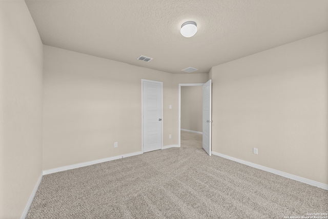 empty room featuring a textured ceiling and carpet