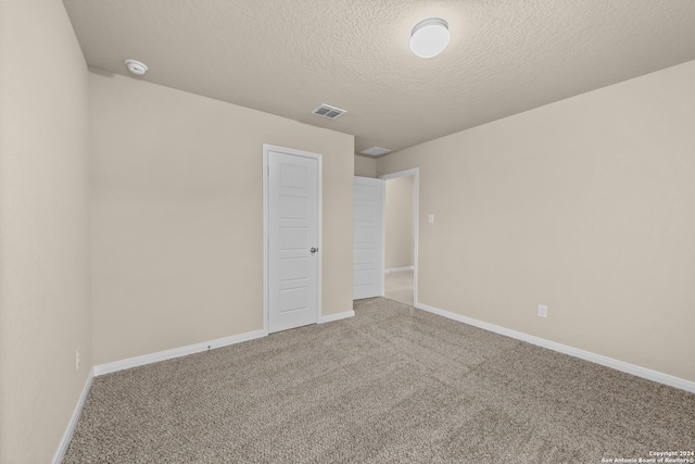 unfurnished room with carpet floors and a textured ceiling