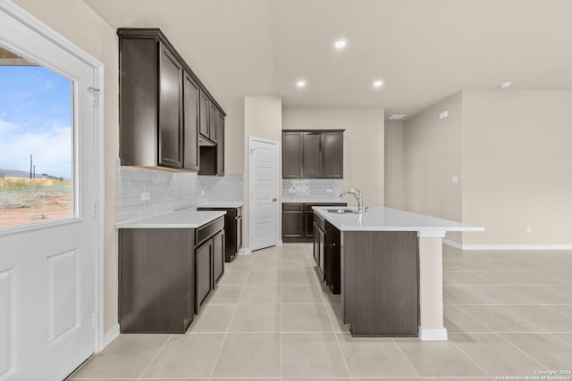 kitchen featuring sink, dark brown cabinetry, a center island with sink, and light tile patterned floors