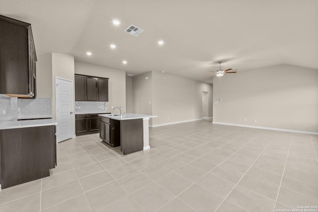 kitchen featuring tasteful backsplash, light tile patterned floors, sink, ceiling fan, and a center island with sink