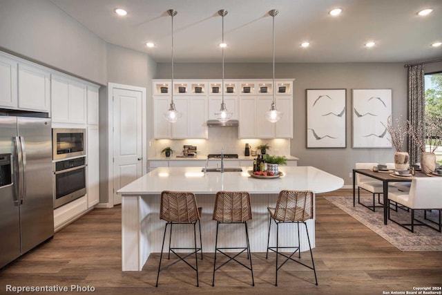 kitchen featuring a center island with sink, appliances with stainless steel finishes, dark hardwood / wood-style floors, and white cabinetry