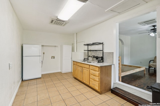 kitchen with sink, backsplash, white fridge, light tile patterned floors, and ceiling fan