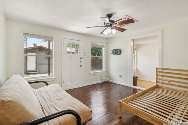 living room featuring ceiling fan, plenty of natural light, dark hardwood / wood-style floors, and a textured ceiling