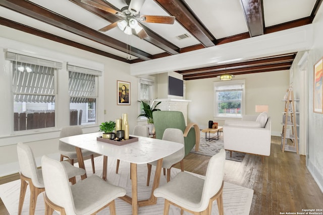 dining space featuring beamed ceiling, a brick fireplace, hardwood / wood-style floors, and ceiling fan