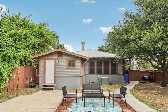 rear view of house with cooling unit, a patio area, and a sunroom