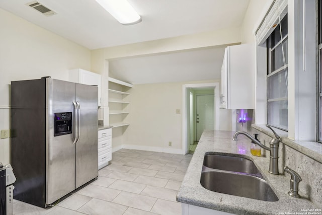 kitchen with white cabinetry, sink, light tile patterned floors, light stone counters, and stainless steel fridge with ice dispenser