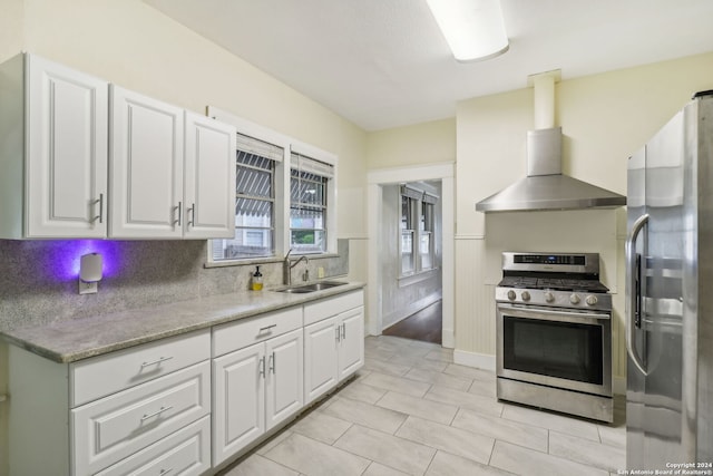 kitchen with wall chimney range hood, sink, white cabinetry, stainless steel appliances, and light stone counters