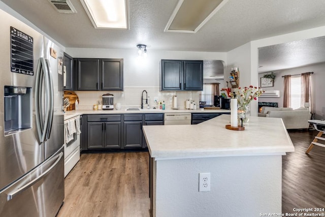 kitchen with white appliances, a textured ceiling, tasteful backsplash, sink, and hardwood / wood-style flooring