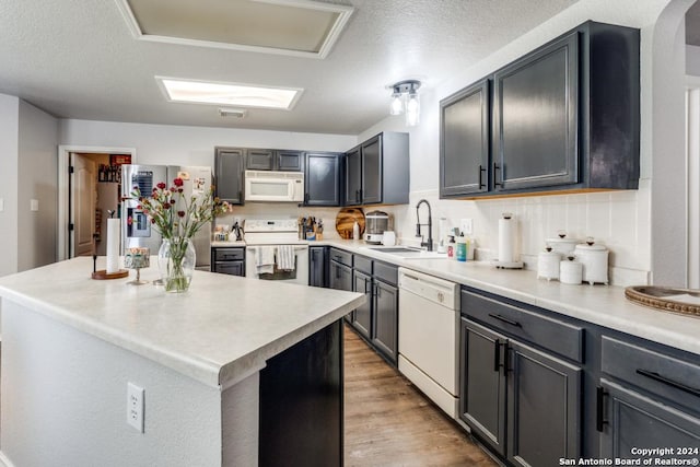 kitchen with white appliances, a center island, decorative backsplash, sink, and gray cabinets