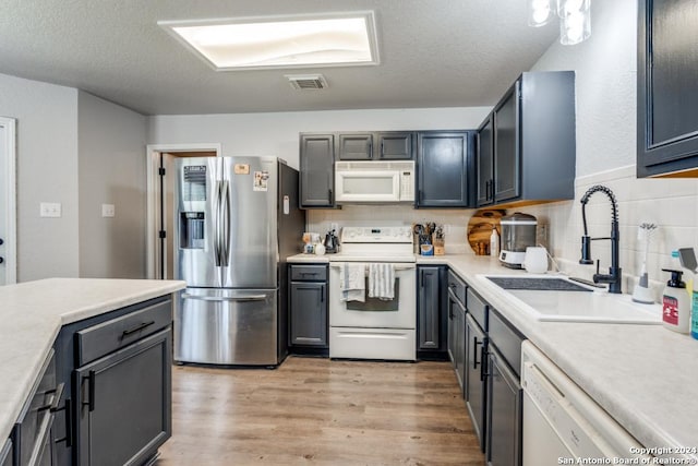 kitchen with sink, white appliances, backsplash, and a textured ceiling