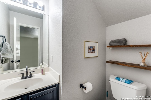 bathroom with a textured ceiling, toilet, lofted ceiling, and vanity