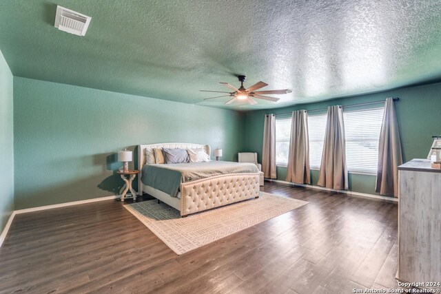 bedroom featuring ceiling fan, a textured ceiling, and dark hardwood / wood-style floors