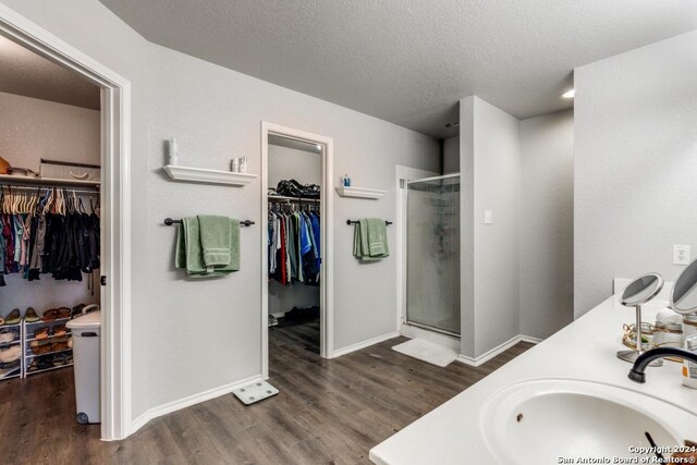 bathroom featuring hardwood / wood-style floors, a textured ceiling, a shower with shower door, and vanity