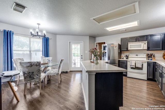 kitchen with white appliances, a center island, decorative light fixtures, wood-type flooring, and a chandelier