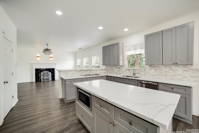 kitchen featuring sink, a center island, appliances with stainless steel finishes, plenty of natural light, and gray cabinets