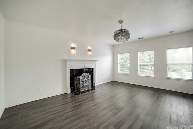 unfurnished living room featuring dark wood-type flooring, a tile fireplace, and a wealth of natural light