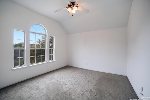 carpeted empty room featuring ceiling fan, vaulted ceiling, and a healthy amount of sunlight