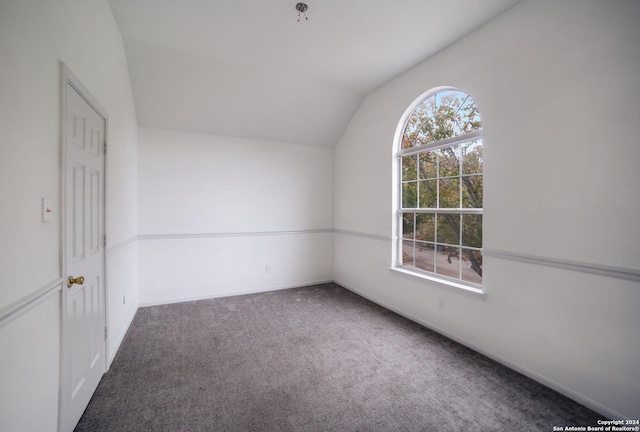 carpeted spare room featuring vaulted ceiling