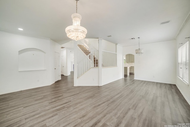 unfurnished living room with a notable chandelier, hardwood / wood-style flooring, and ornamental molding